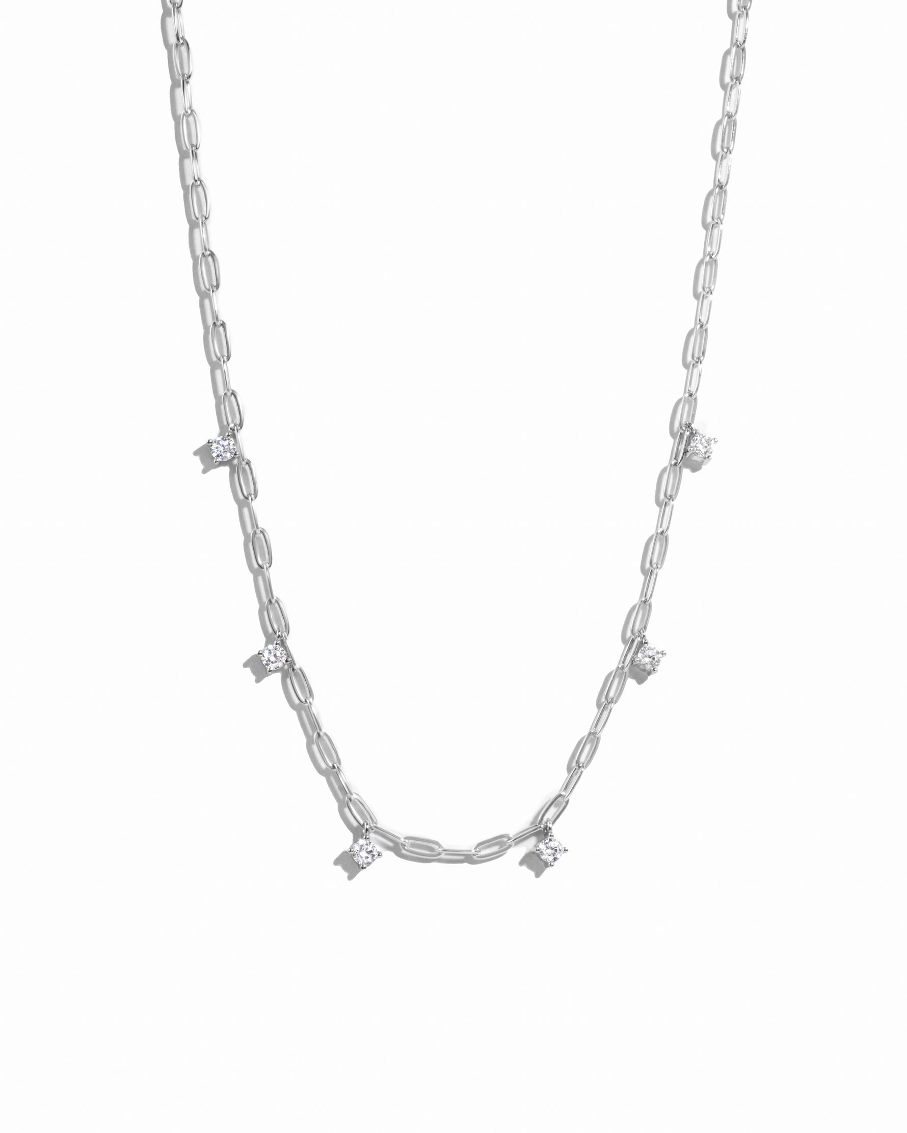 Dainty silver paperclip chain necklace with cz charms hanging off of it. 