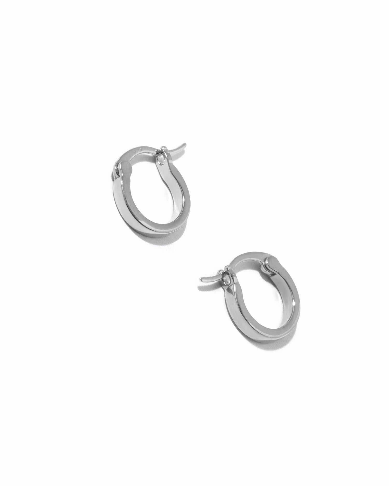 Delicate sterling silver small flat hoop earrings on white background.