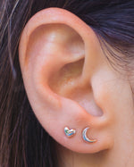 Model wearing sterling silver plain moon stud earrings paired with tiny silver heart studs