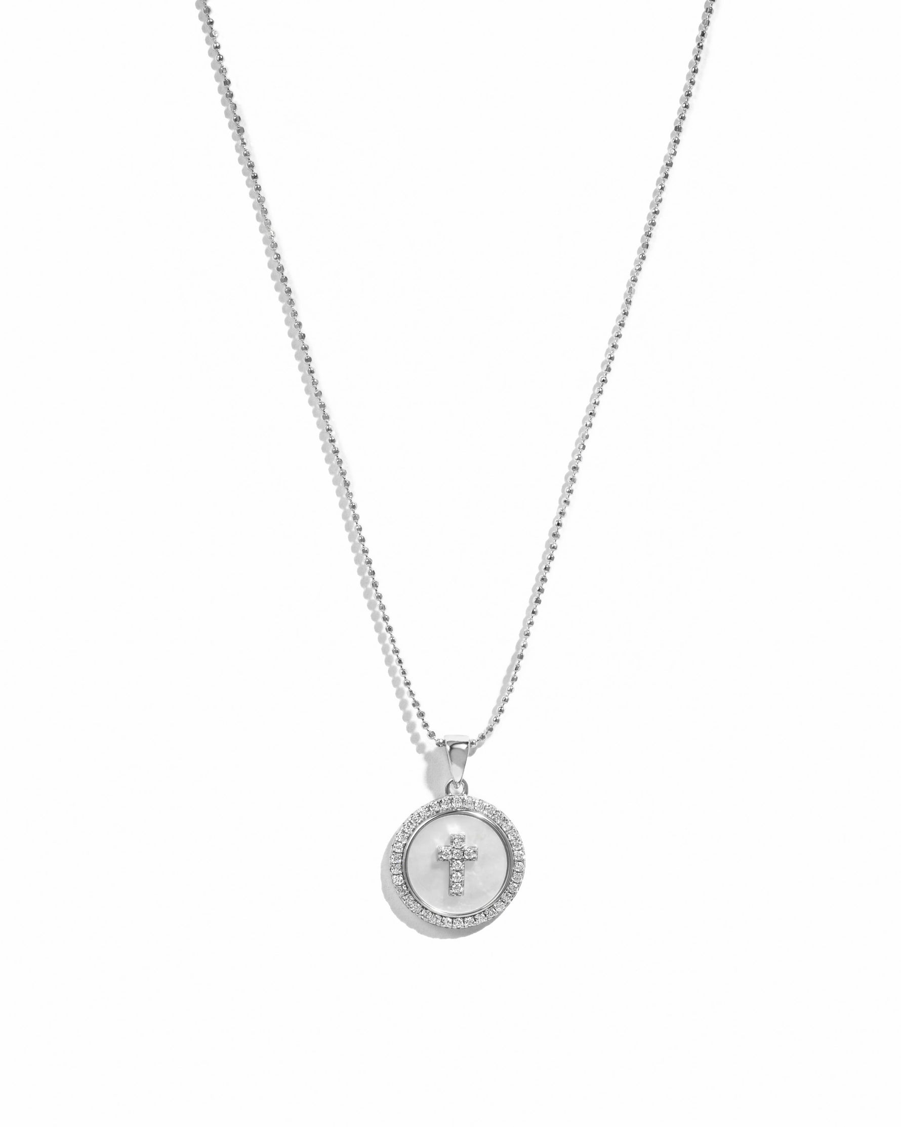Silver mother of pearl cross necklace with a circular pendant from Sami Jewels, featuring elegant, shiny pearl accents.