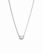Delicate silver opal halo pendant necklace on white background.