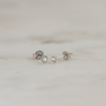 Tiny sterling silver opal vibrant stud earrings on marble background.