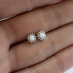 Model holding delicate opal and cz stud earrings in silver. 