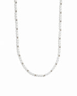 Silver beads and pearl beaded necklace on white background.