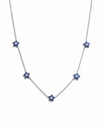 Silver sapphire flower charm necklace on white background.