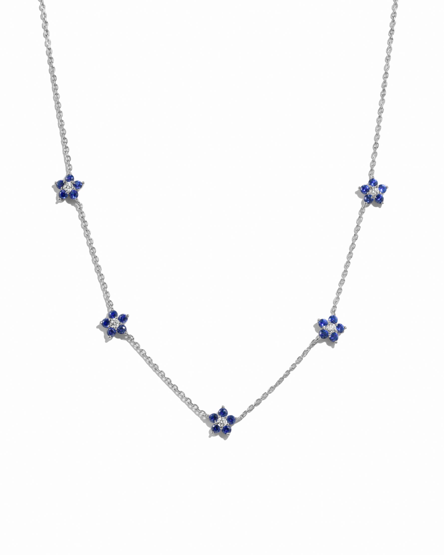 Silver sapphire flower charm necklace on white background.