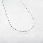 Silver delicate turquoise enamel beaded necklace on marble background.