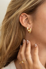 Model wearing trendy gold hoops