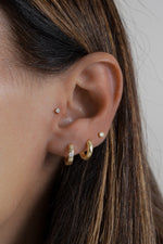 Model wearing everyday gold hoops with a diamond bezel stud earring