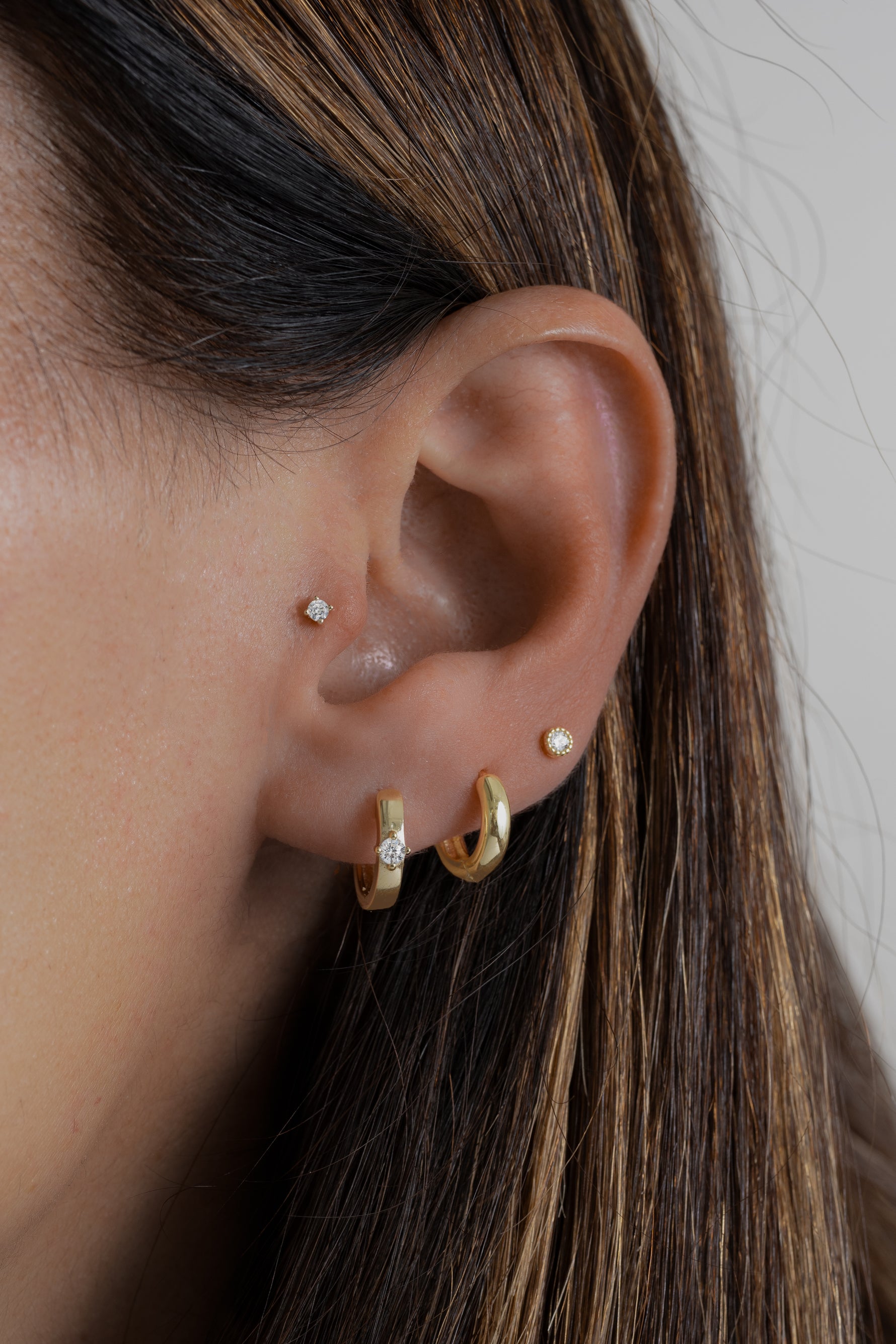 Model wearing everyday gold hoops with a diamond bezel stud earring