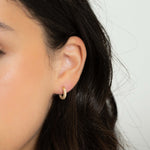 Model wearing classic gold everyday diamond studded hoop earrings. 
