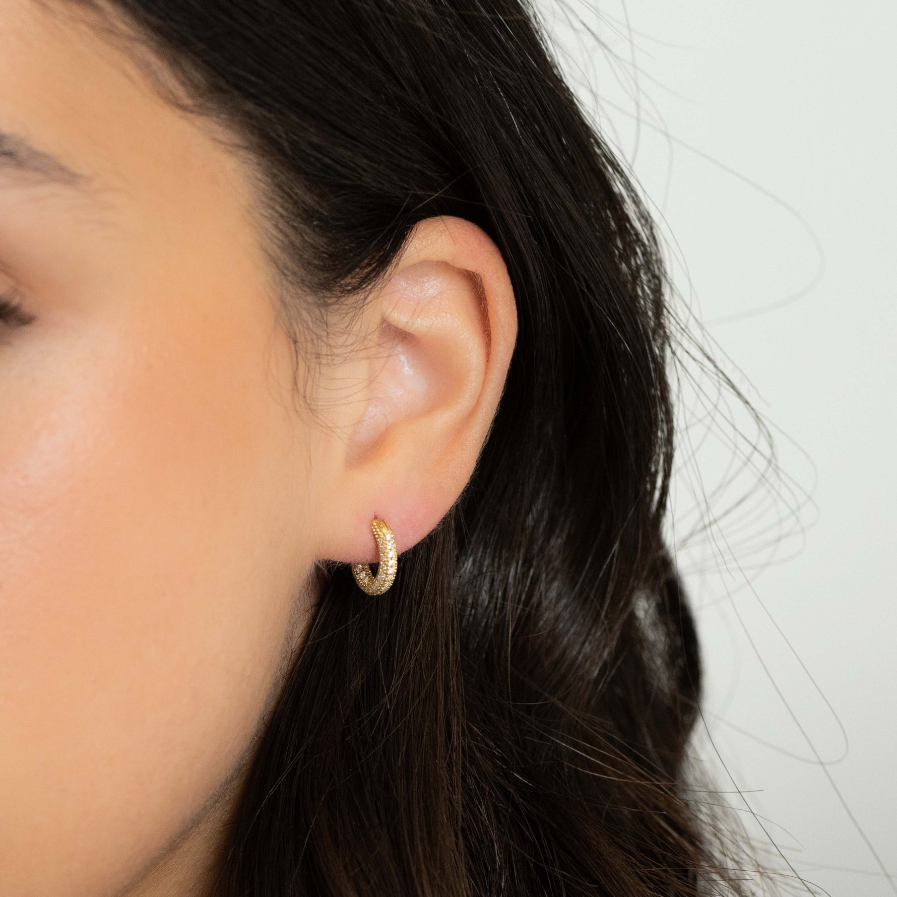 Model wearing classic gold everyday diamond studded hoop earrings. 