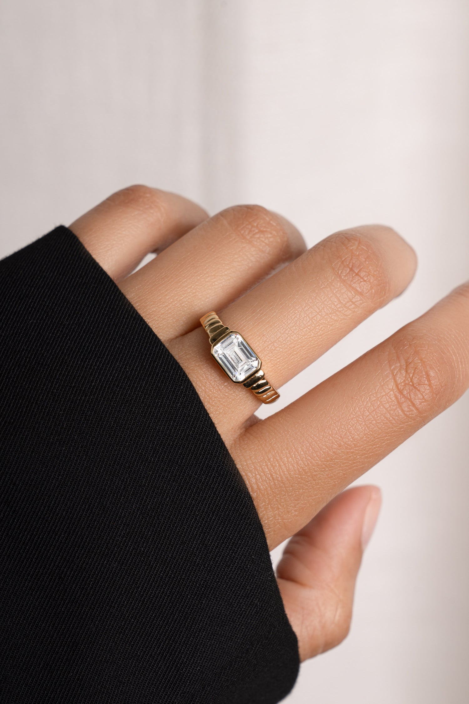 Model wearing gold statement ring with cz emerald-cut diamond. 