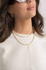 Model wearing diamond tennis necklace and gold rope chain necklace.