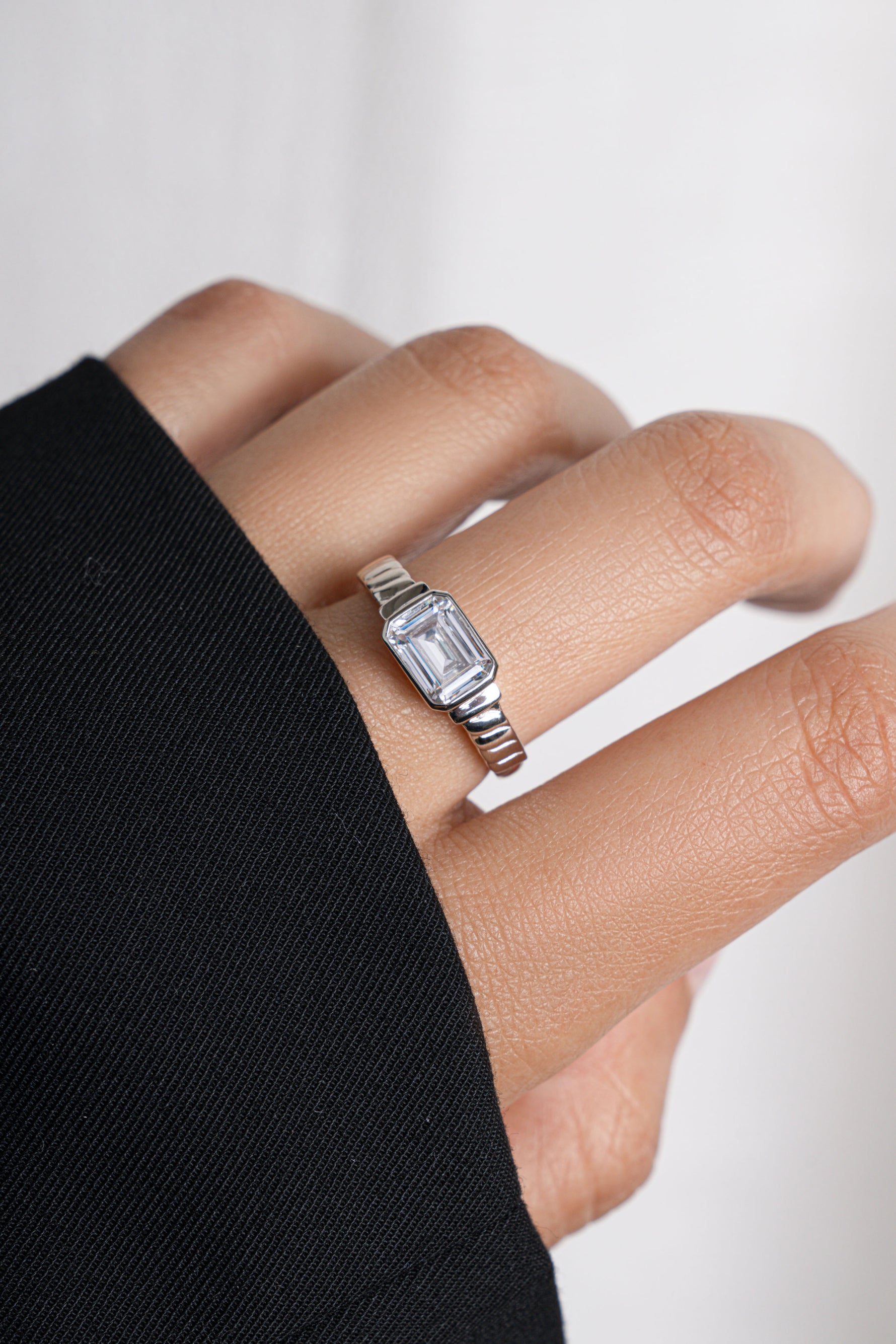 Model wearing statement silver ring with emerald-cut cz diamond. 