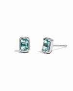 Elegant aquamarine birthstone baguette stud earrings with sterling silver metal on white background.