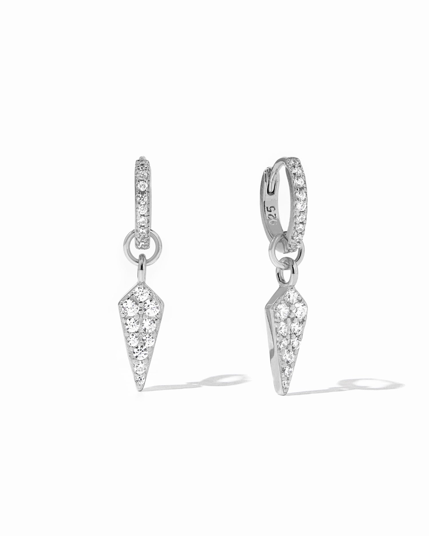 Delicate sterling silver CZ dagger charm huggies with removable charm on white background.
