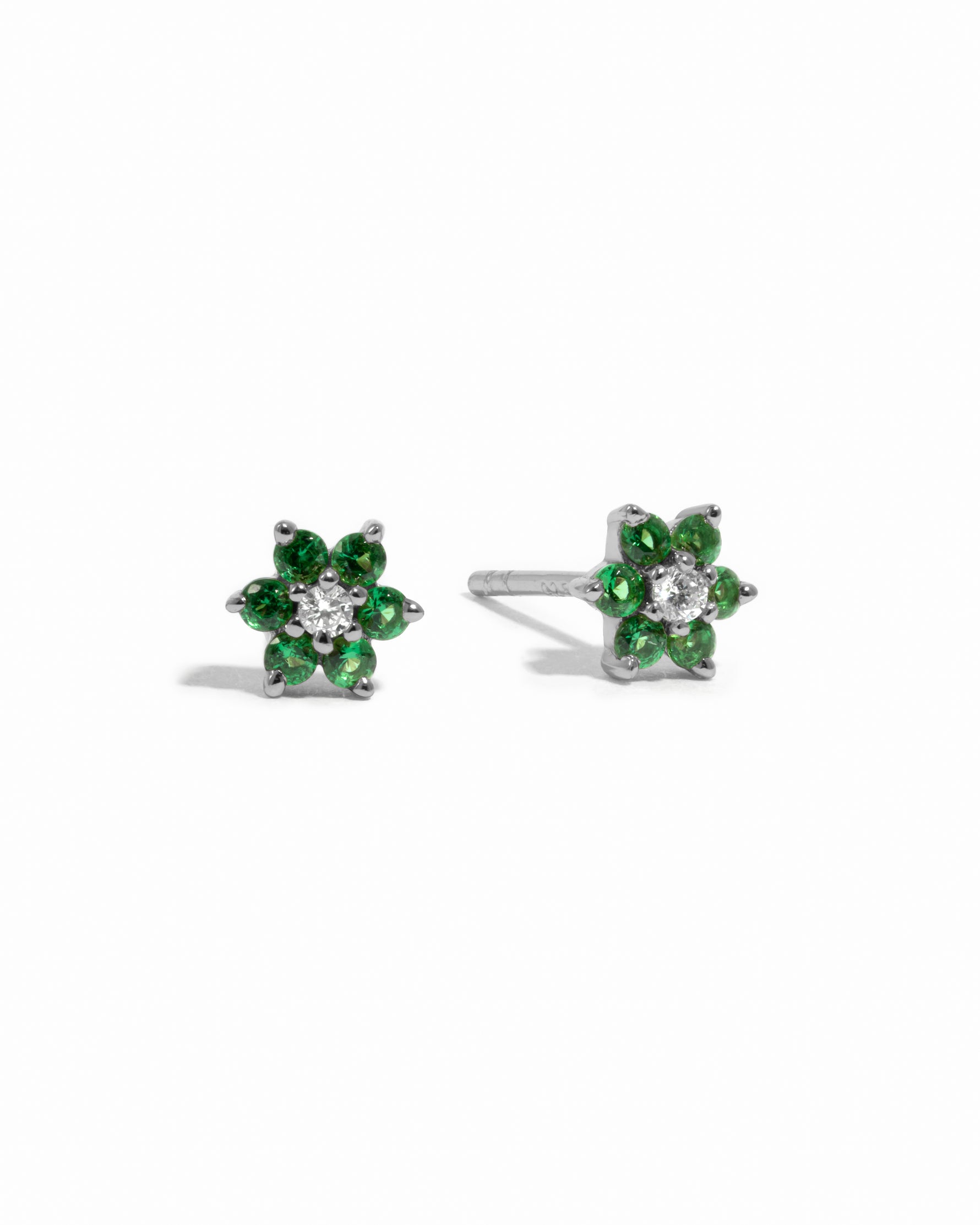 Dainty sterling silver emerald birthstone flower stud earrings with white diamond in the center on white background.