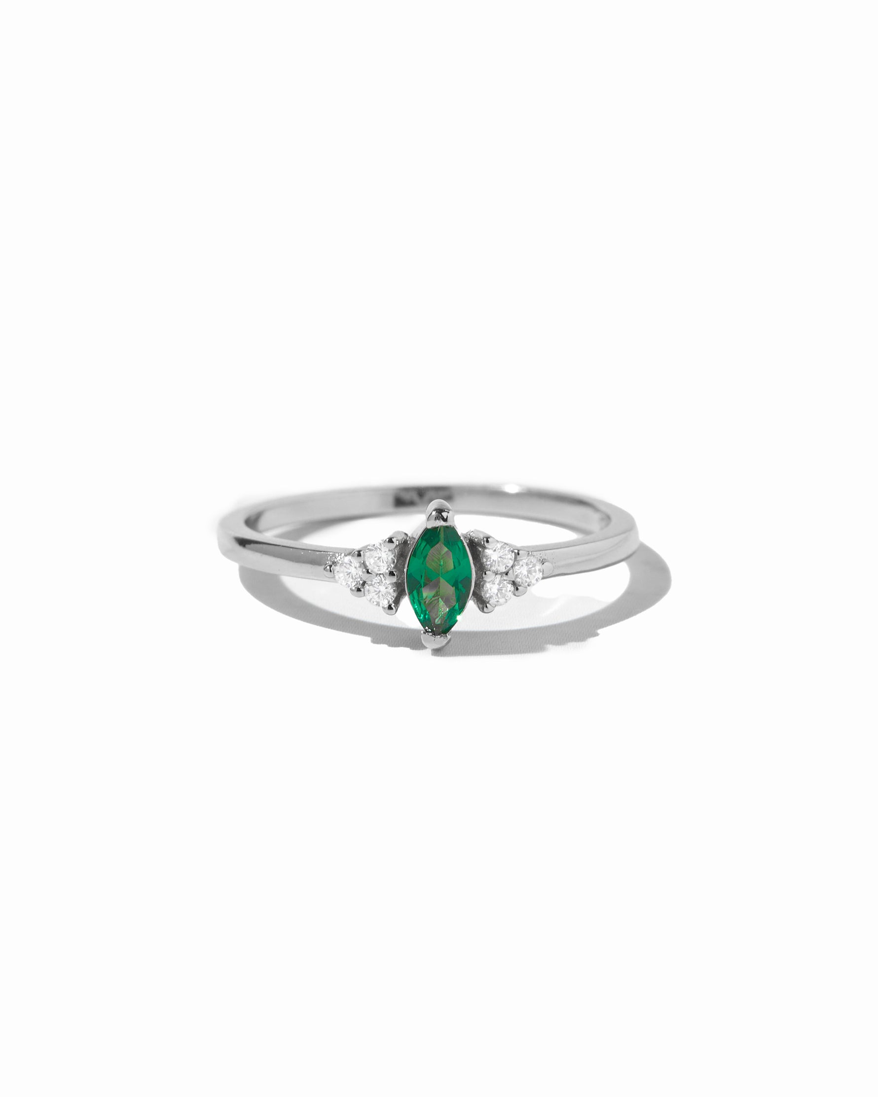 Emerald marquise birthstone ring in silver on white background.