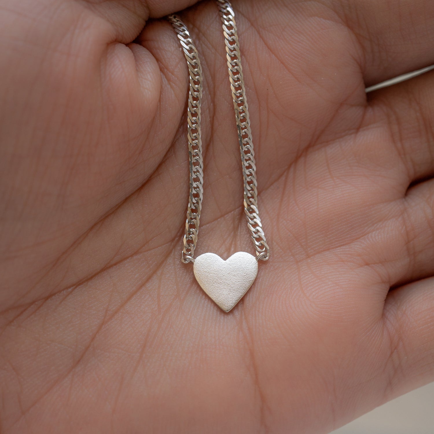 Silver heart pendant necklace on chain link necklace.