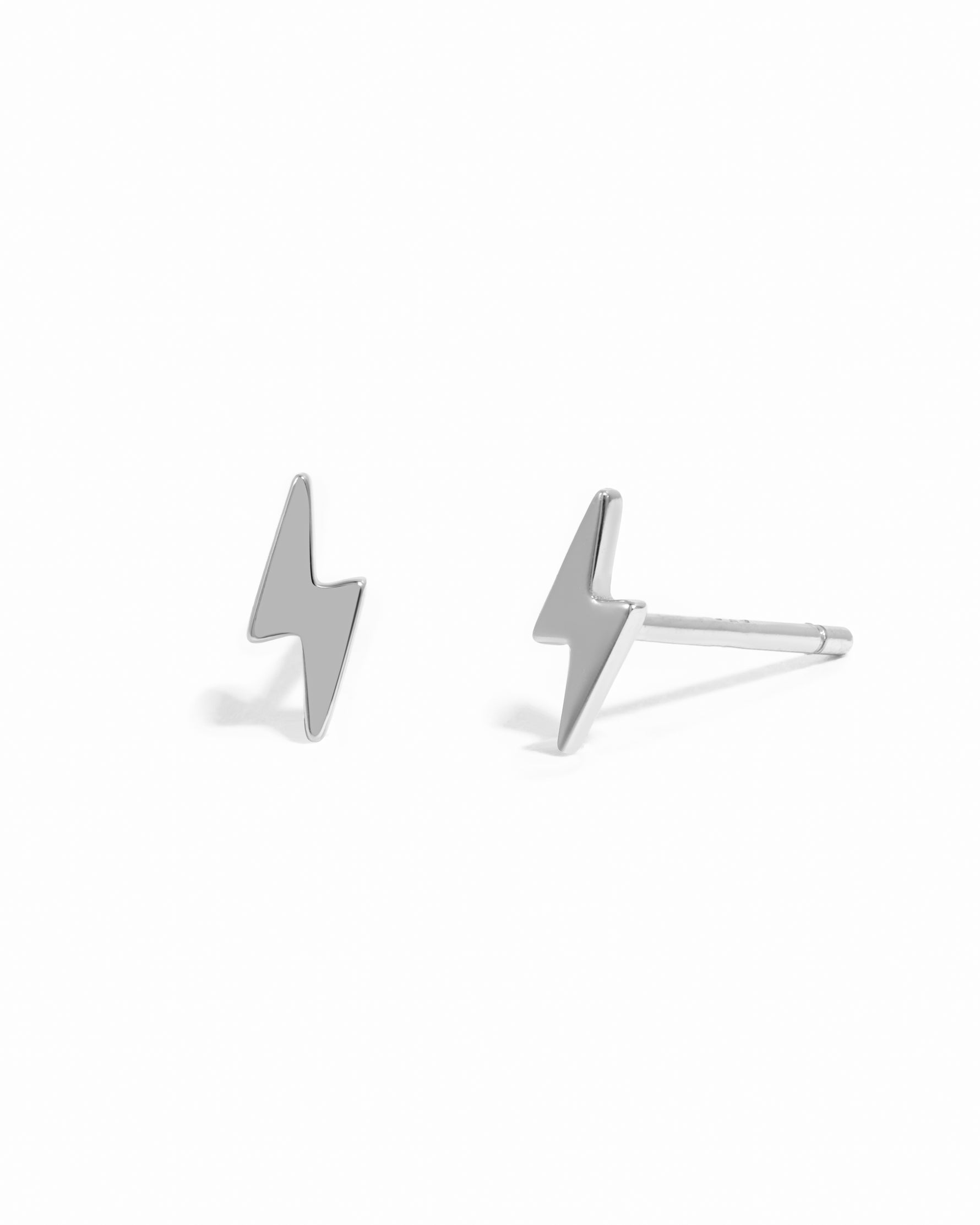 Dainty silver lightning bolt stud earrings on white background.