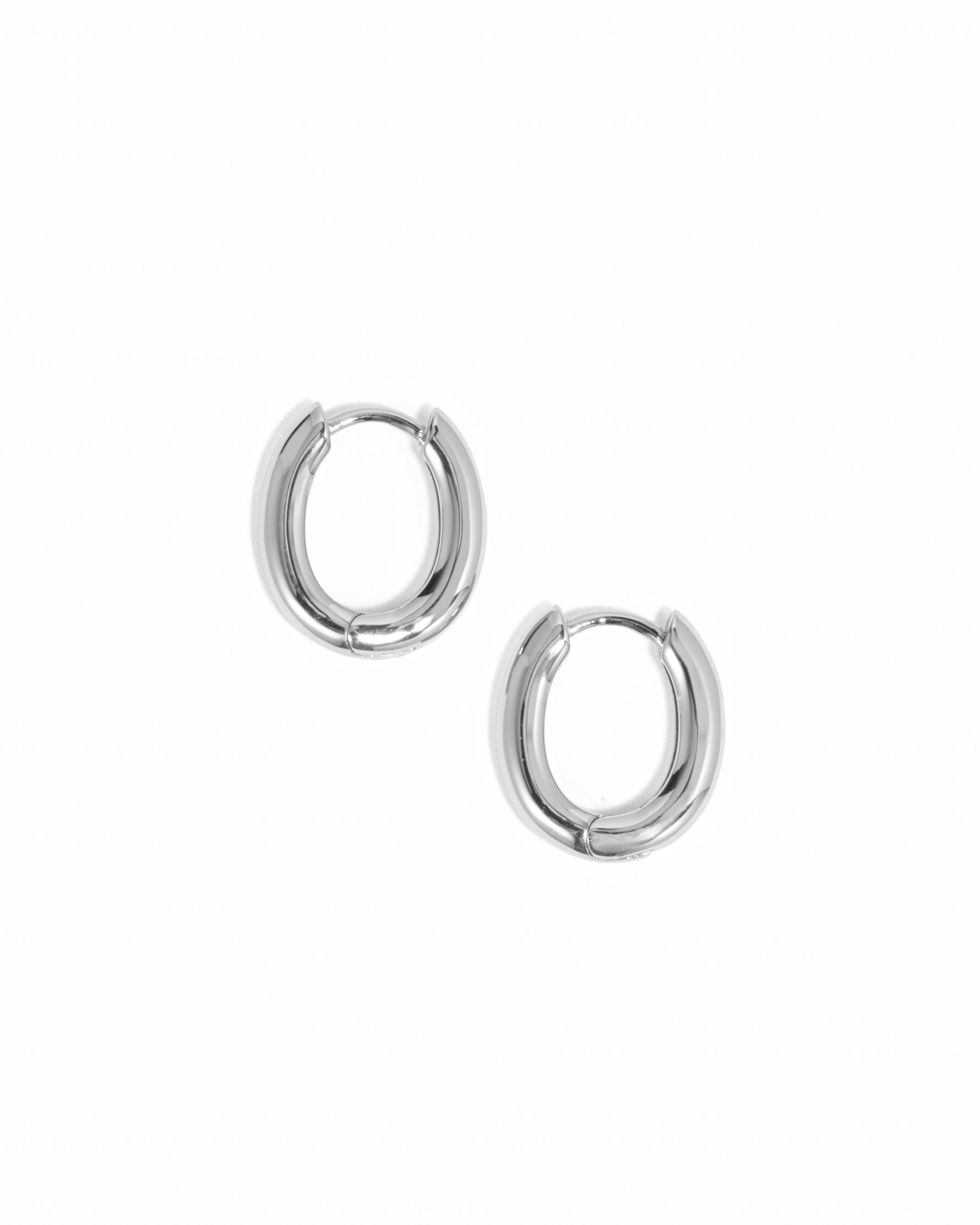 Minimalist oval silver huggie hoops on white background