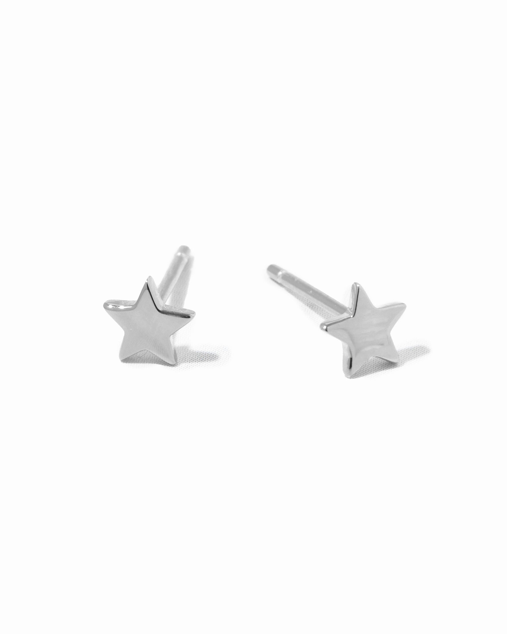 Dainty sterling silver star studs on white background.