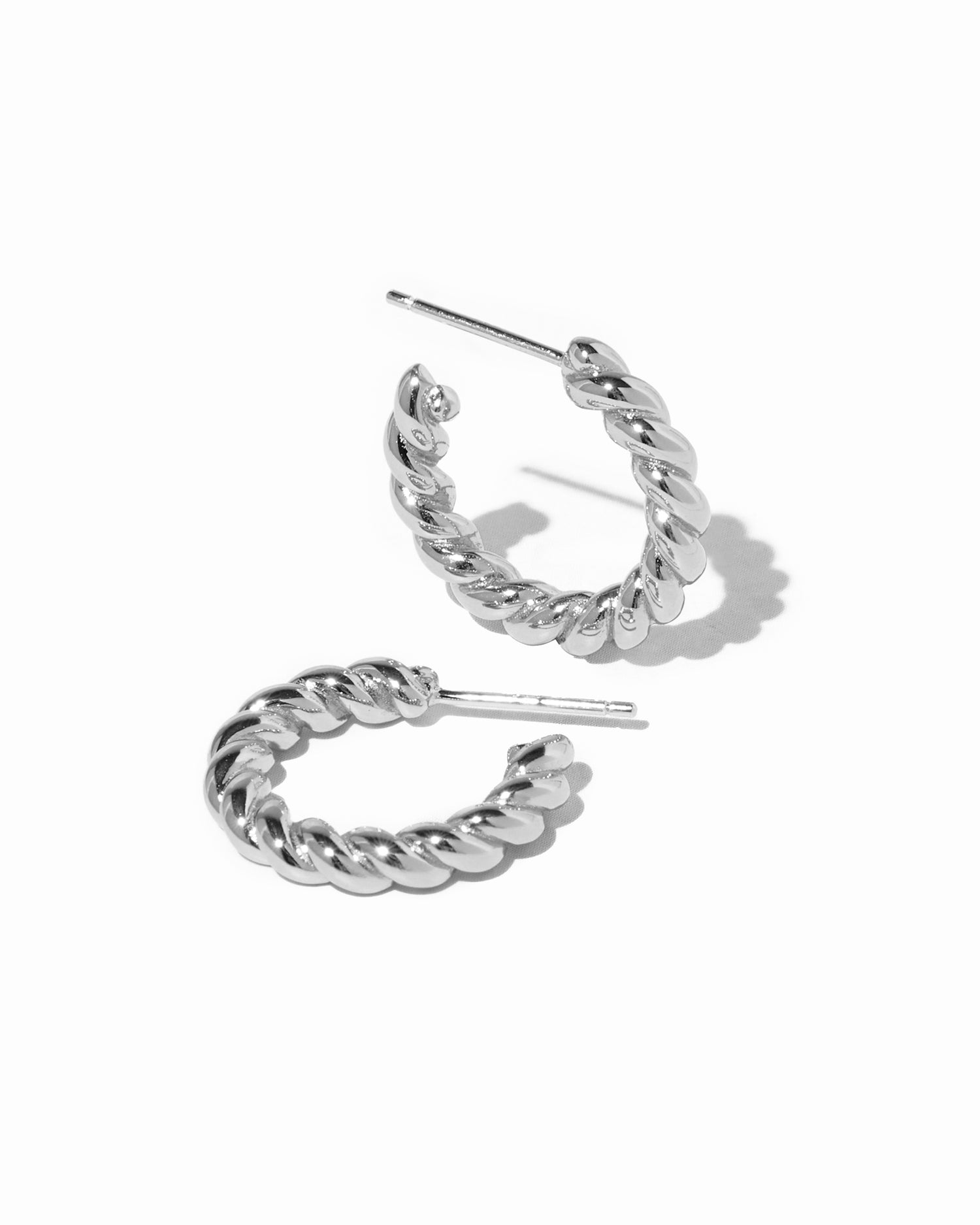 Sterling silver spiral textured hoop earrings on white background