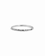 Sterling silver thin plain hammered band on white background.