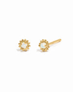 Dainty gold opal center sunburst stud earrings on white background.