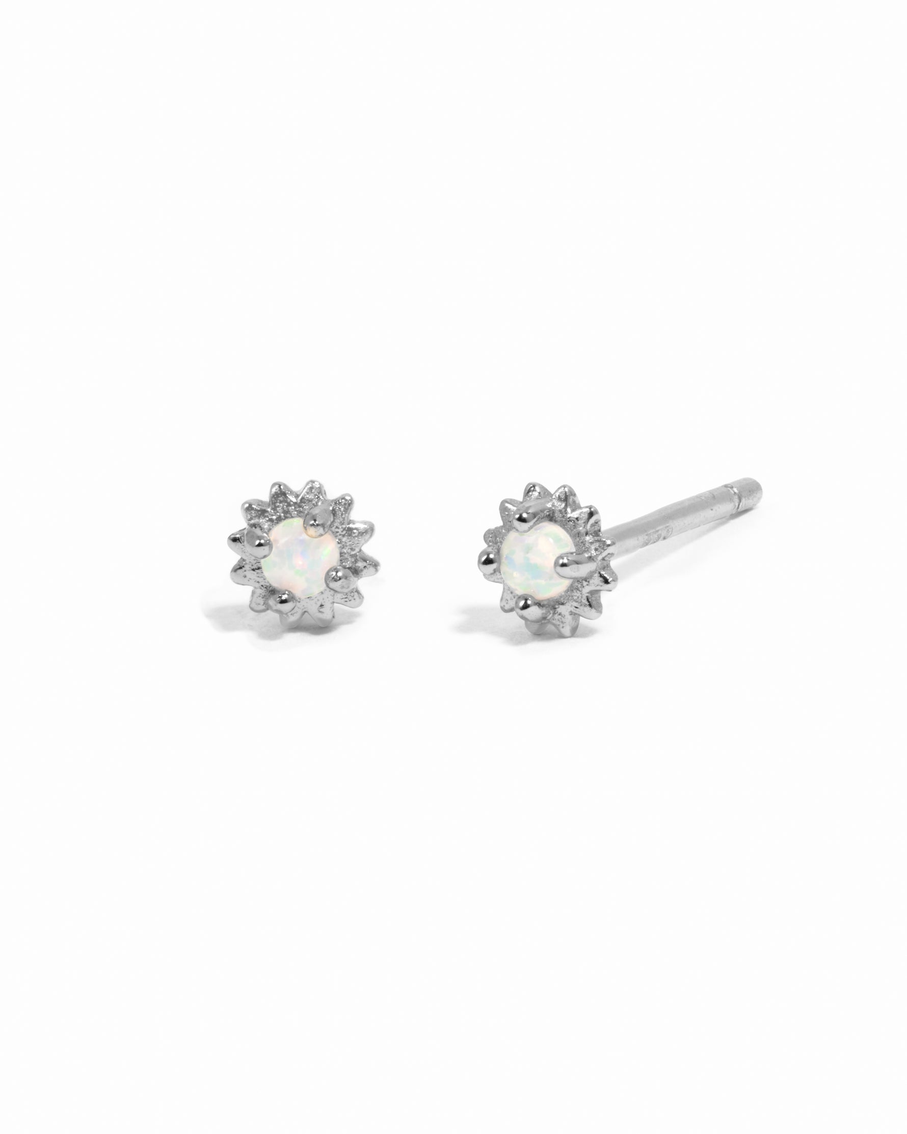 Dainty sterling silver opal center sunburst stud earrings on white background.