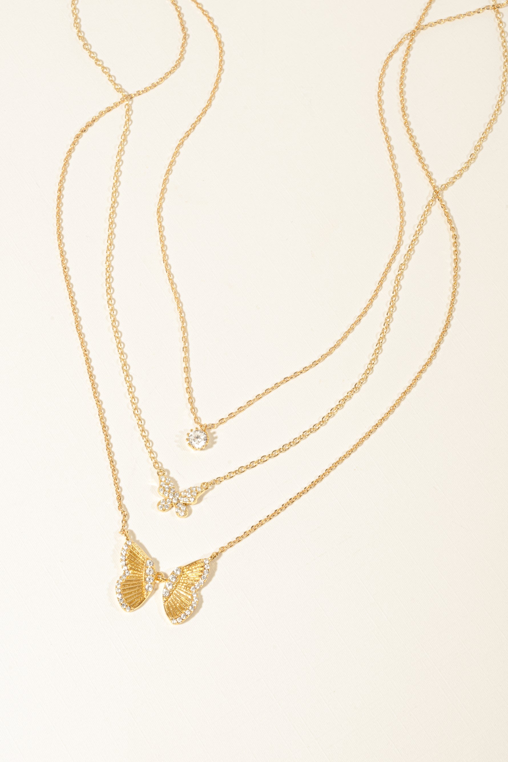 Gold butterfly necklace stack featuring a dainty tiny bezel necklace, a cz butterfly necklace, and a statement butterfly necklace. 