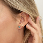 Model wearing minimalist earring stack featuring gold turquoise flower studs and tiny gold flower stud earrings. 