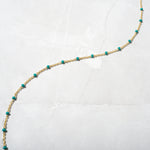 Minimalist gold beaded turquoise necklace on marble background. 