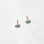 Gold flower stud earrings on marble background. 