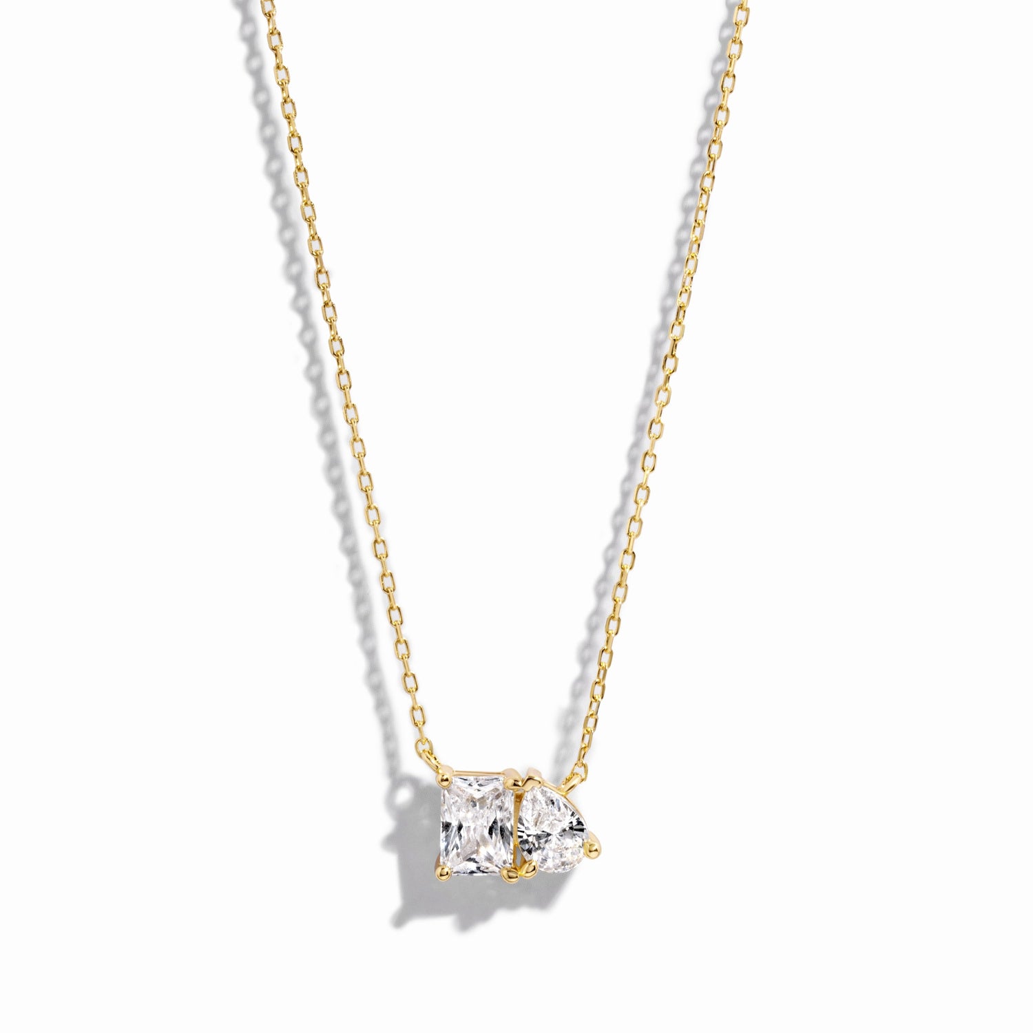 closeup image of gold necklace with pear and emerald cut stone