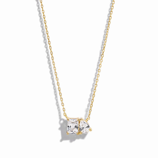 closeup image of gold necklace with pear and emerald cut stone