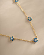Close-up of Sami Jewels Aqua Flower Necklace featuring a gold chain and detailed aqua flower pendant.