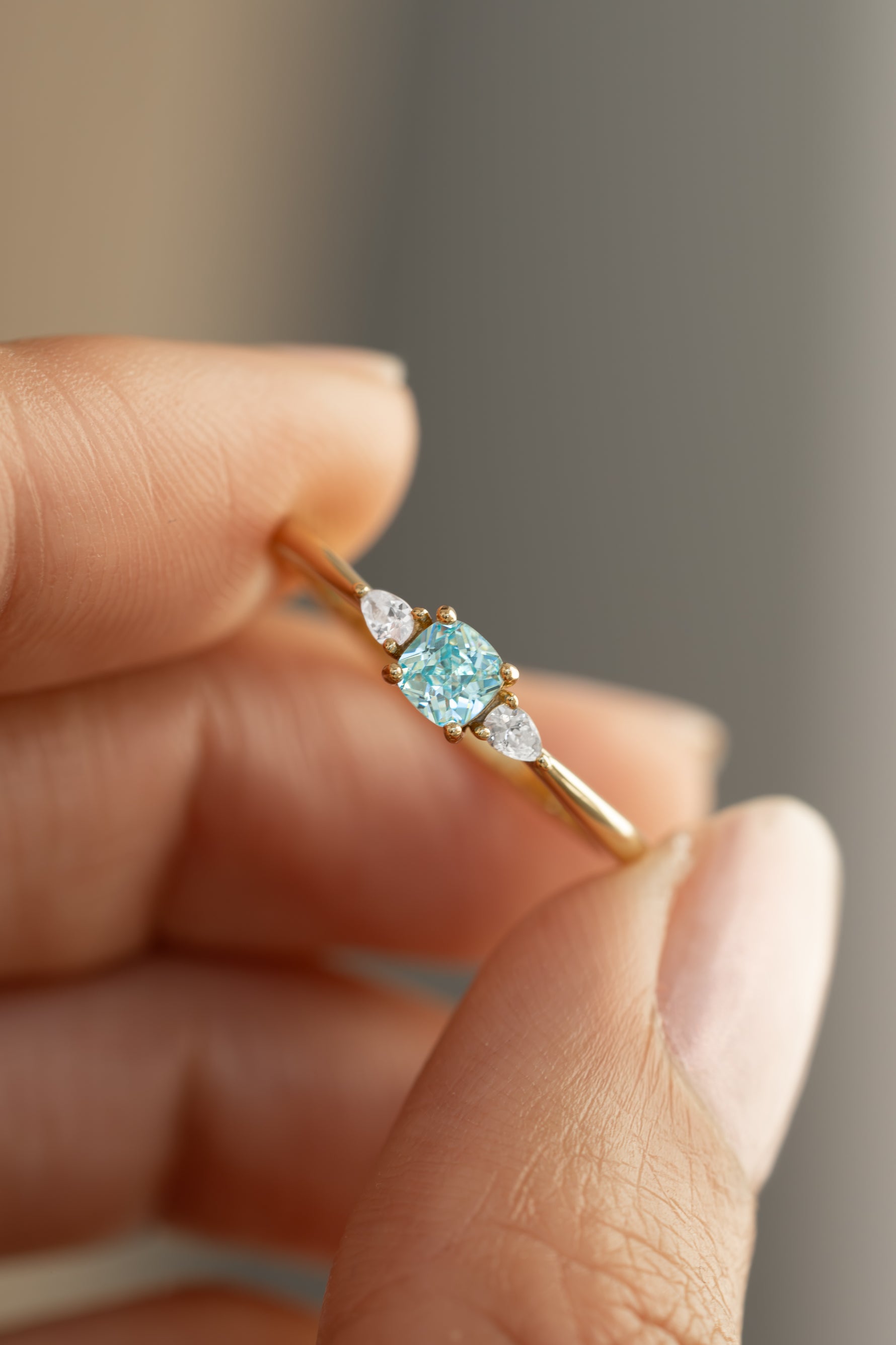 aquamarine cushion ring in gold held between two fingers