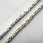 closeup image of gold aquamarine tennis bracelet and silver aquamarine bracelet