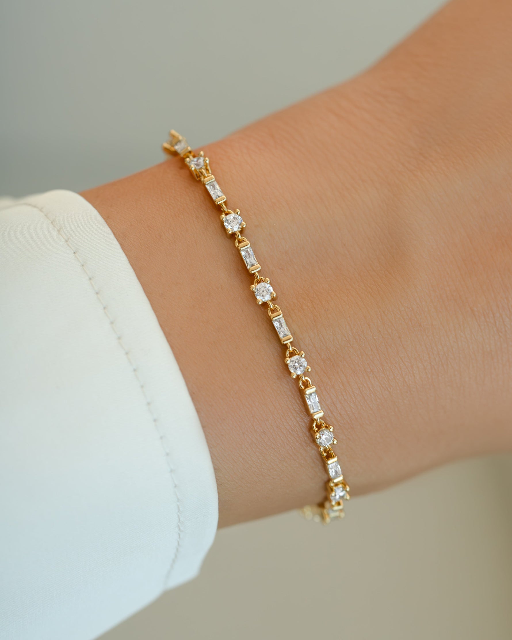 Gold bracelet featuring baguette and solitaire diamonds from Sami Jewels, displayed on a model's wrist.