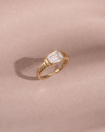 gold diamond baguette cut statement ring light pink background 