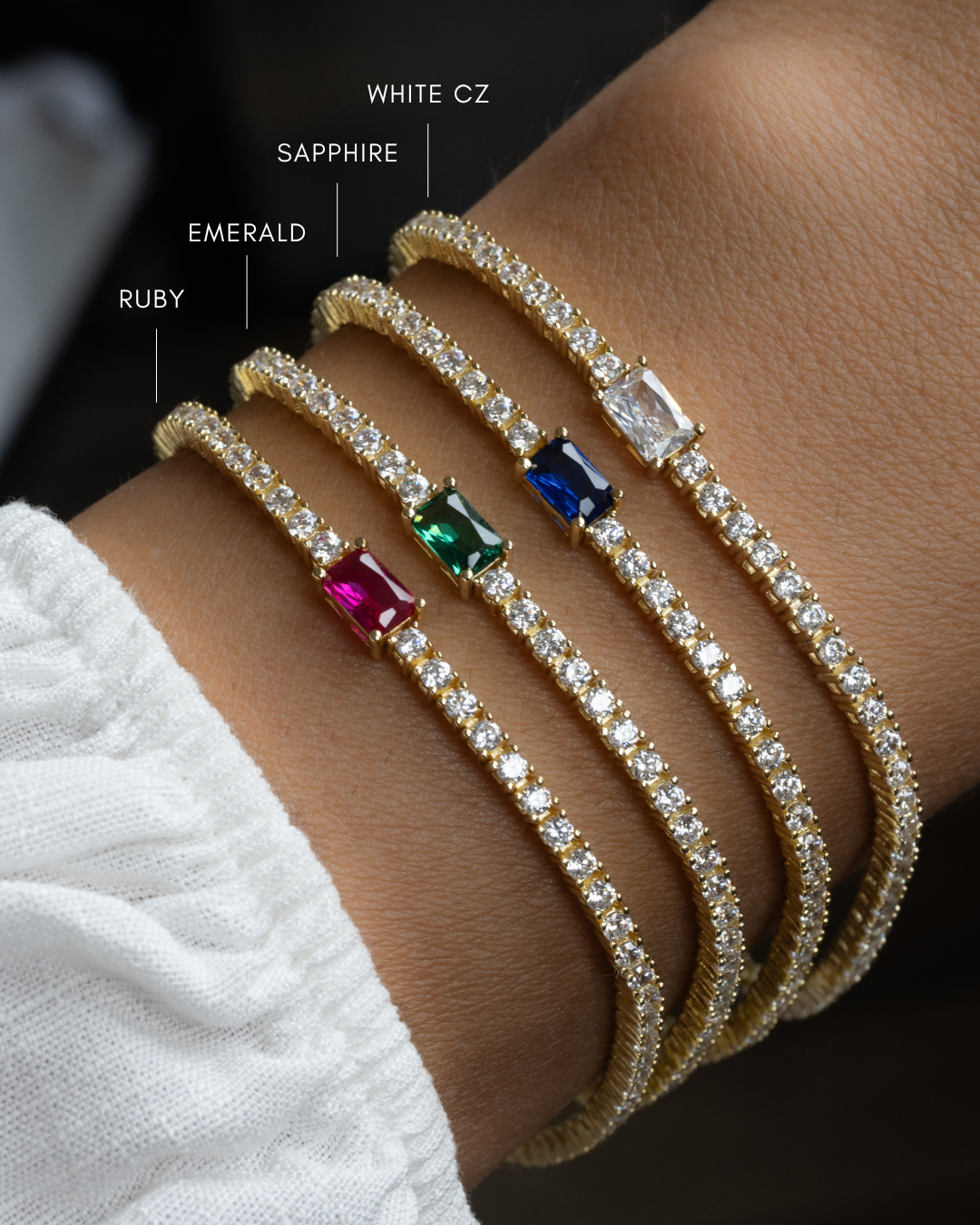 Sami Jewels tennis bracelet with baguette diamonds and colorful birthstone charms on a model's wrist.