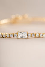 Close-up of Sami Jewels gold tennis bracelet featuring a baguette diamond charm and elegant design.