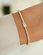 Gold tennis bracelet with baguette diamond charm worn on a model's wrist by Sami Jewels.