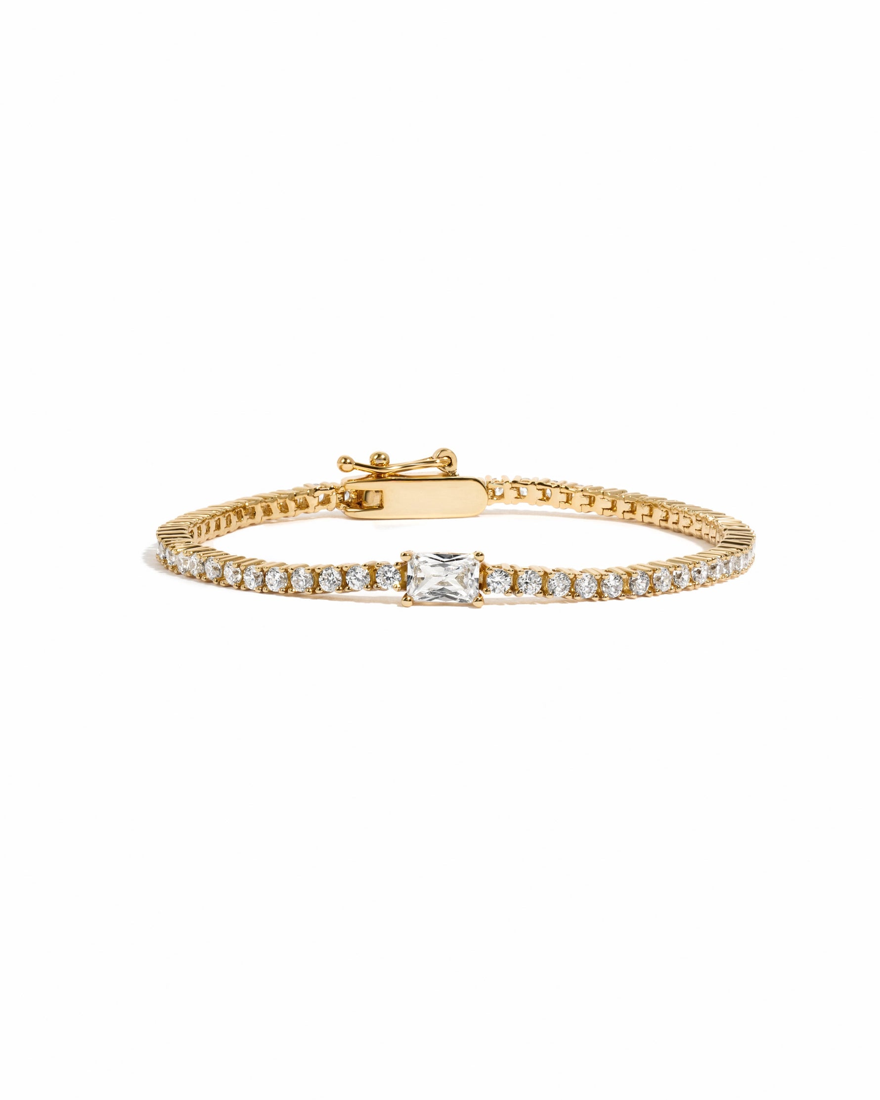Gold tennis bracelet with baguette diamond charms by Sami Jewels displayed on a white background.