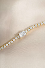 Gold tennis bracelet with baguette diamond charms and stone accents by Sami Jewels.