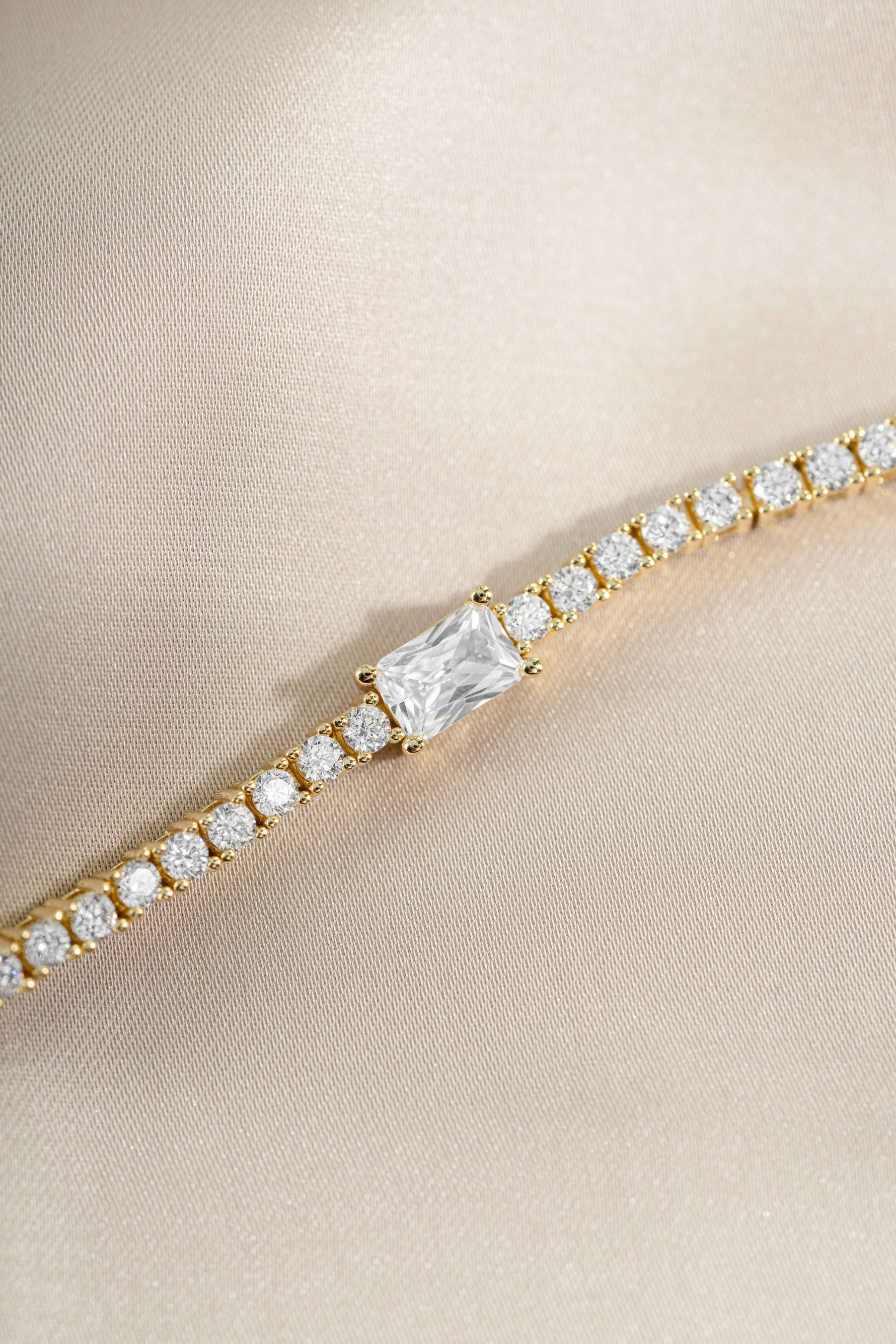 Gold tennis bracelet with baguette diamond charms and stone accents by Sami Jewels.