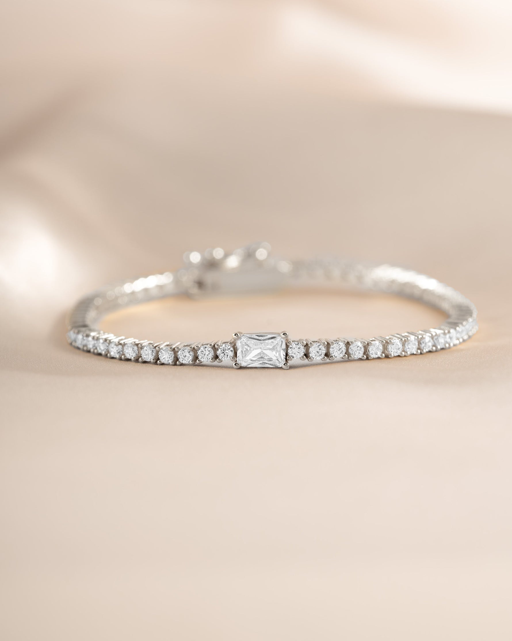 Silver tennis bracelet by Sami Jewels with baguette cubic zirconia charms and sparkling diamond accents.