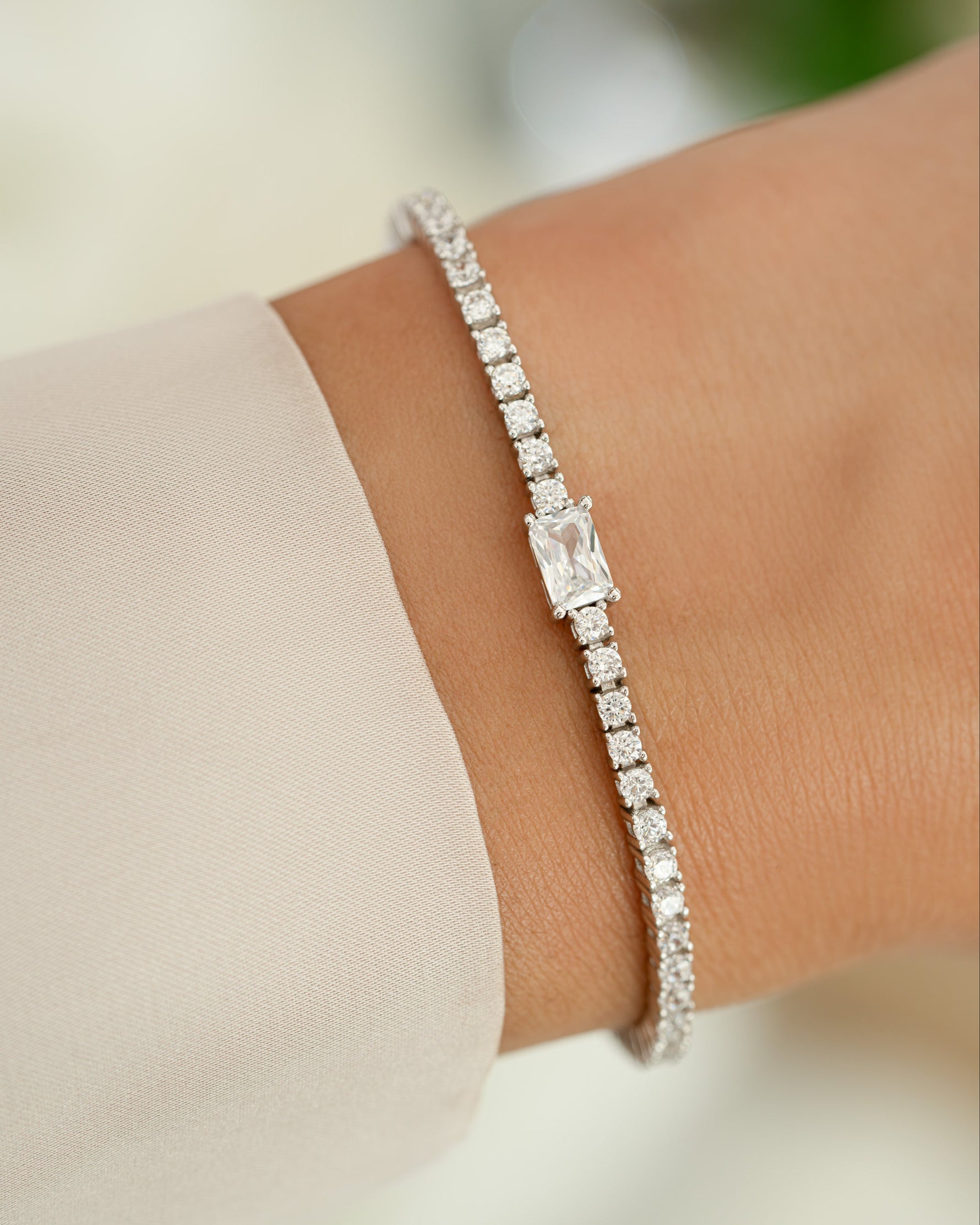 Silver tennis bracelet with baguette diamond charms worn on a model, showcasing elegant jewelry by Sami Jewels.